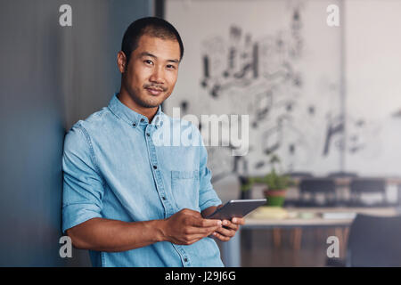 Confident Asian designer using a tablet in a modern office Stock Photo