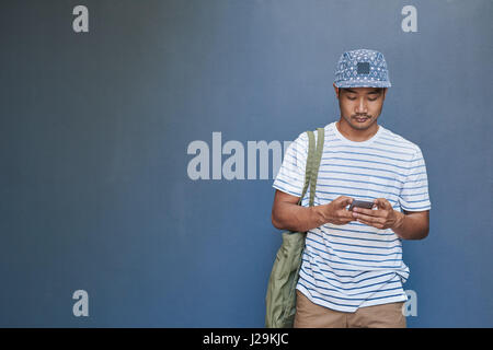 Stylish young Asian man reading a text message outside Stock Photo