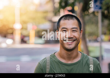 Young Asian man smiling confidently on a city street Stock Photo