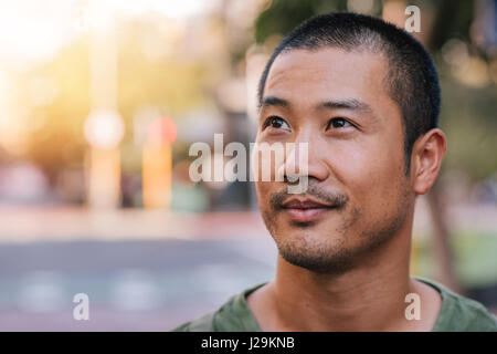 Handsome young Asian man standing on a city street Stock Photo