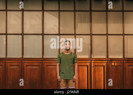 Stylish young Asian man standing in front of windows outside Stock Photo