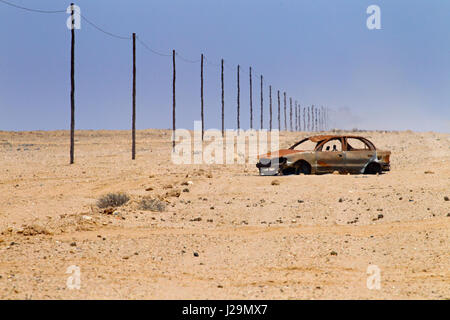 Endless gravel road the C35 and wrecked car Namibia desert region Stock Photo