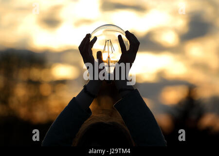 Energy light bulb from sunset on hand concept Stock Photo