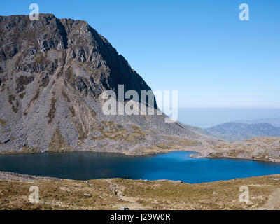 The cliffs of Cyfrwy rise over Llyn y Gadair, a lake beneath the summit of Cadair Idris, a mountain in Snowdonia, North Wales. Stock Photo