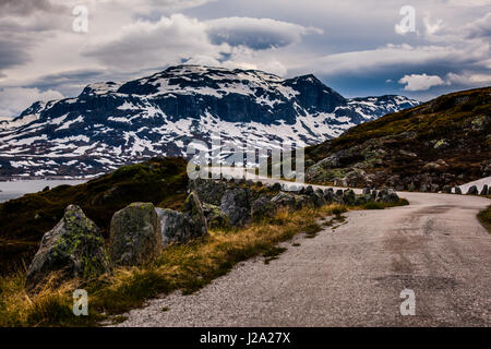 Gravel road on Hardangervidda, Norway, an autumn day with snow on the mountain tops. Stock Photo