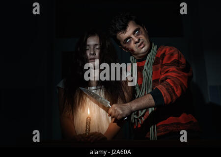 Terrible the man threatens with a knife to the terrible woman. Stock Photo