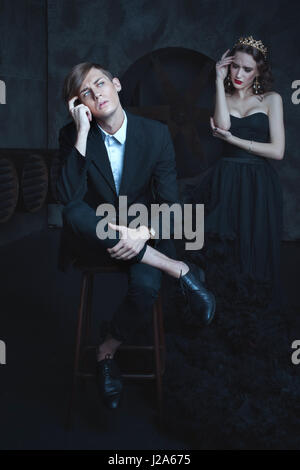 Stylish guy dreams, in the background a sad queen. Stock Photo