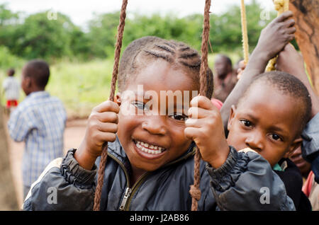 Malawi, Mzimba district, Chilumba Community Based Childcare Centre (CBCC). Smiling children playing on wooden swing Stock Photo