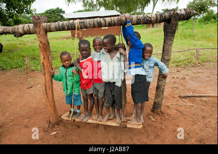 Malawi, Mzimba district, Chilumba Community Based Childcare Centre (CBCC). Smiling children playing on wooden swing Stock Photo