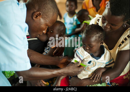 Malawi, Northern Region, Rumphi, Health Surveillance Assistant (HSA) Bruno Banda checks the breathing rate of 2 year old Grace Norma who is diagnosed with malaria. Grace takes LA assisted by her mother Christina Phiri. Stock Photo