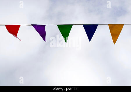 Colored pennant garland in the wind against cloudy sky Stock Photo