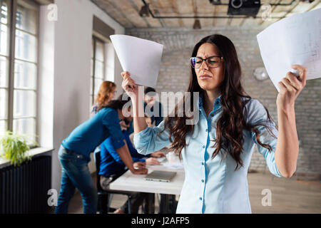 Overworked stressful businesswoman overwhelmed with papers in office Stock Photo