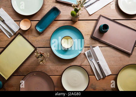 Handmade earthenware and cutlery on a table, overhead shot Stock Photo