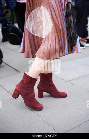 LONDON - FEBRUARY, 2017: Low section of woman wearing chiffon and lace pleated skirt with suede ankle boots in the street during London Fashion Week, vertical, side view Stock Photo