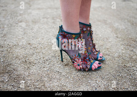 LONDON - FEBRUARY, 2017: Low section detail of woman wearing open toe stiletto heel shoes decorated with appliqué flowers during London Fashion Week, horizontal, side view Stock Photo