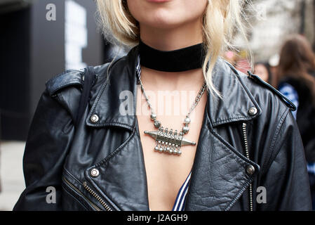 LONDON - FEBRUARY, 2017: Close up crop of  woman wearing a black leather jacket, black choker and a silver tribal necklace in the street during London Fashion Week, horizontal, front view Stock Photo