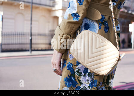 LONDON - FEBRUARY, 2017: Mid section of woman wearing white Chanel cross body handbag and coat with floral decoration in street during London Fashion Week Stock Photo