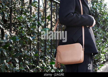 LONDON - FEBRUARY, 2017: Mid section of woman wearing brown Gucci cross body handbag standing in street during London Fashion Week Stock Photo