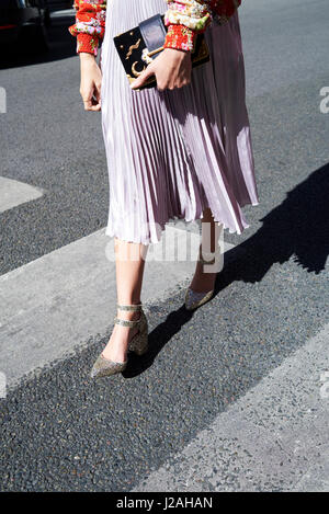 Woman in pleated skirt walks holding designer handbag, crop Stock Photo