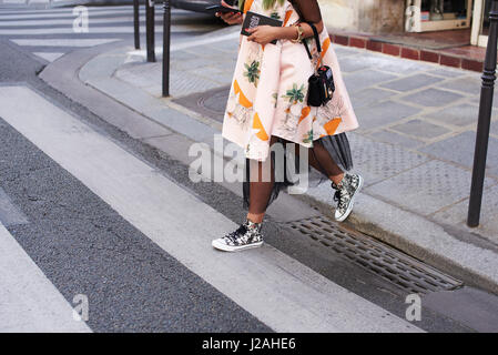 Trendy young woman holding book crossing street, side view Stock Photo