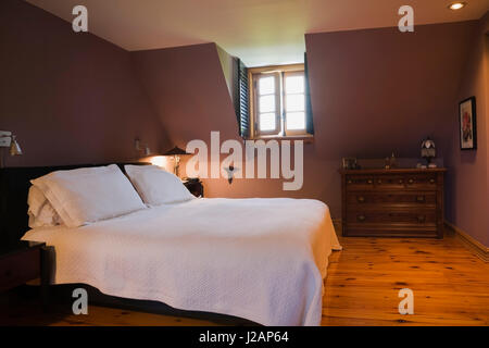 Bed and antique wooden dresser in the master bedroom on the upsatirs floor inside a stacked log home Stock Photo
