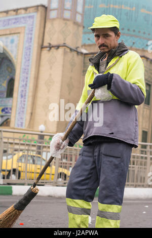 Tehran Province- IRAN-December 1, 2016 A Portrait of An Urban Street Cleaner Man Holding Hand-made Sweeping Tool By Gloved Hand in Front of Mosque Bui Stock Photo