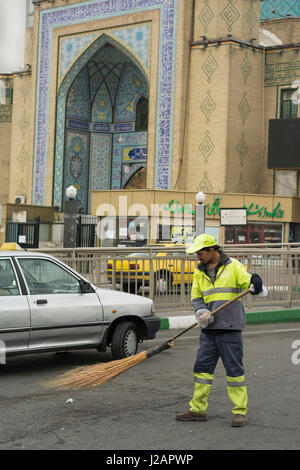 Tehran Province- IRAN-December 1, 2016 A Portrait of An Urban Street Cleaner Man Holding Hand-made Sweeping Tool By Gloved Hand in Front of Mosque Bui Stock Photo