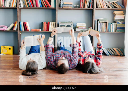 Students are laying on the floor and using books while working together at homework. Education concept. Stock Photo