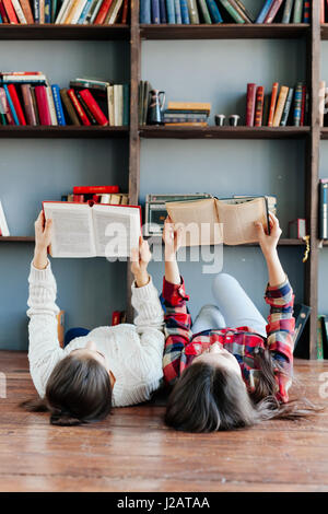 Students are laying on the floor and using books while working together at homework. Education concept. Stock Photo