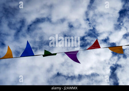Colored pennant garland in the wind against cloudy sky Stock Photo