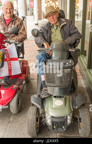 Two adult men, one of whom uses a wheelchair, are smiling inside a van ...