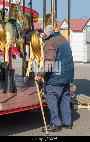 Fairground horses being painted by a senior man before the season begins. Stock Photo
