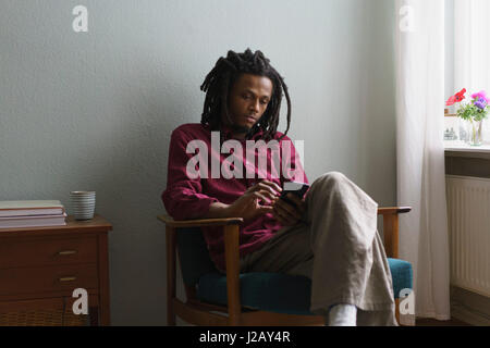 Young man using smart phone while sitting on armchair at home Stock Photo