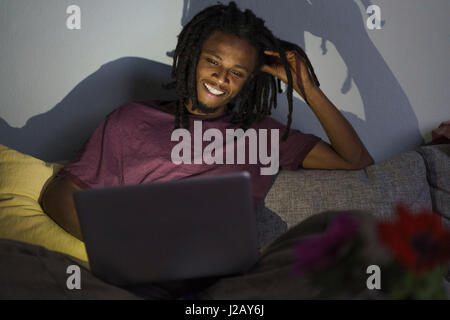Happy man using laptop while sitting on sofa at home Stock Photo