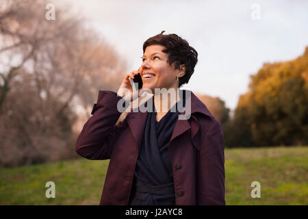 Happy mid adult woman using smart phone at field Stock Photo