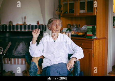 Thoughtful senior woman looking away while sitting on armchair at home Stock Photo