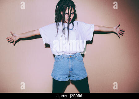 Portrait of woman standing with arms outstretched against brown background Stock Photo