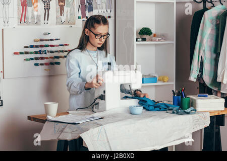 Female fashion designer using sewing machine at design studio Stock Photo