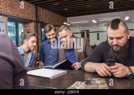 Happy male hairdressers at bar counter in barber shop Stock Photo