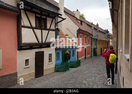 Tourists take photographs using a smartphone in front of the tiny medieval house number 19 in Golden Line in Prague Castle in Prague, Czech Republic. Stock Photo