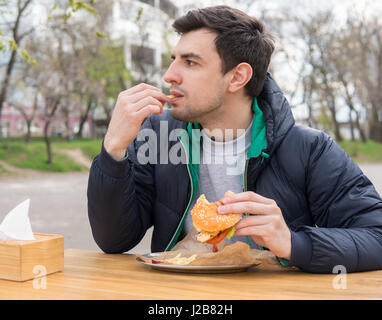 man is eating French fries in a snack bar Stock Photo