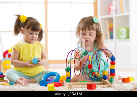 Adorable kids toddlers playing with colorful toys and teacher in ...