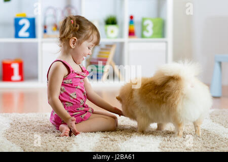 Cute kid girl sitting on the floor with her dog Stock Photo