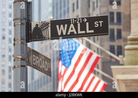 Wall Street sign near Stock Exchange with US flags, financial district in New York in a sunny day Stock Photo