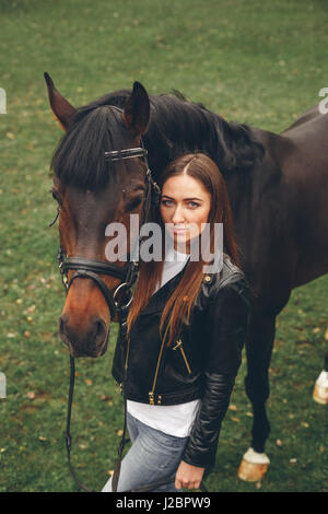 Beautiful girl communicates with a horse in the park Stock Photo