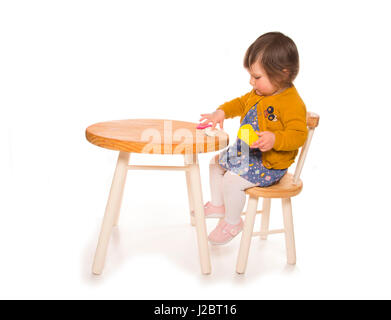 toddler sitting at a table playing with playdough cutout Stock Photo