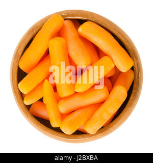 Baby carrots in wooden bowl. Cooked small sized and immature carrots. Root vegetable with orange color. Daucus carota. Isolated macro photo. Stock Photo