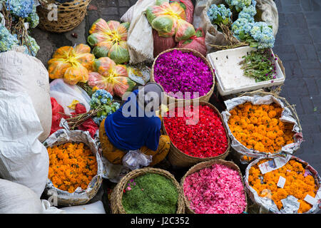 Indonesia, Bali. Pasar Kumbasari outdoor Bali flower market. Flowers are used daily by Balinese Hindus as symbolic offerings at temples and are neatly placed on small hand woven trays made from fresh coconut palm fronds. Stock Photo