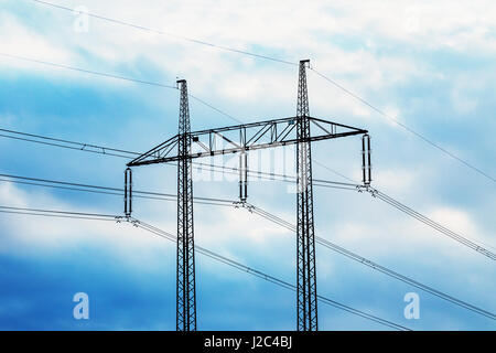 electricity transmission pylon silhouetted against blue sky at dusk Stock Photo