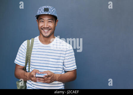 Smiling young Asian man using a cellphone outside Stock Photo